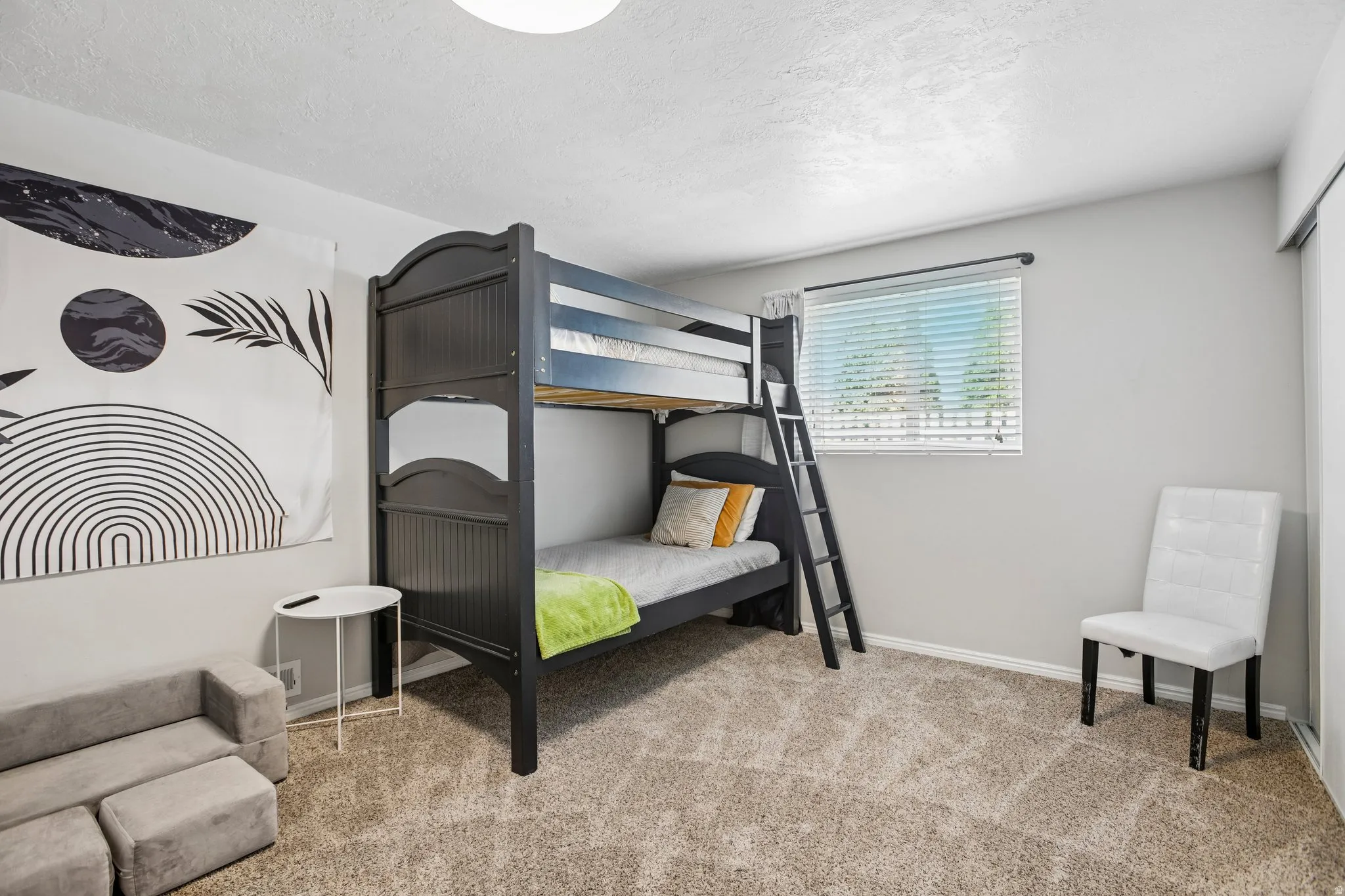 Neutral gray painted walls, light brown textured carpeting, and a window with blinds