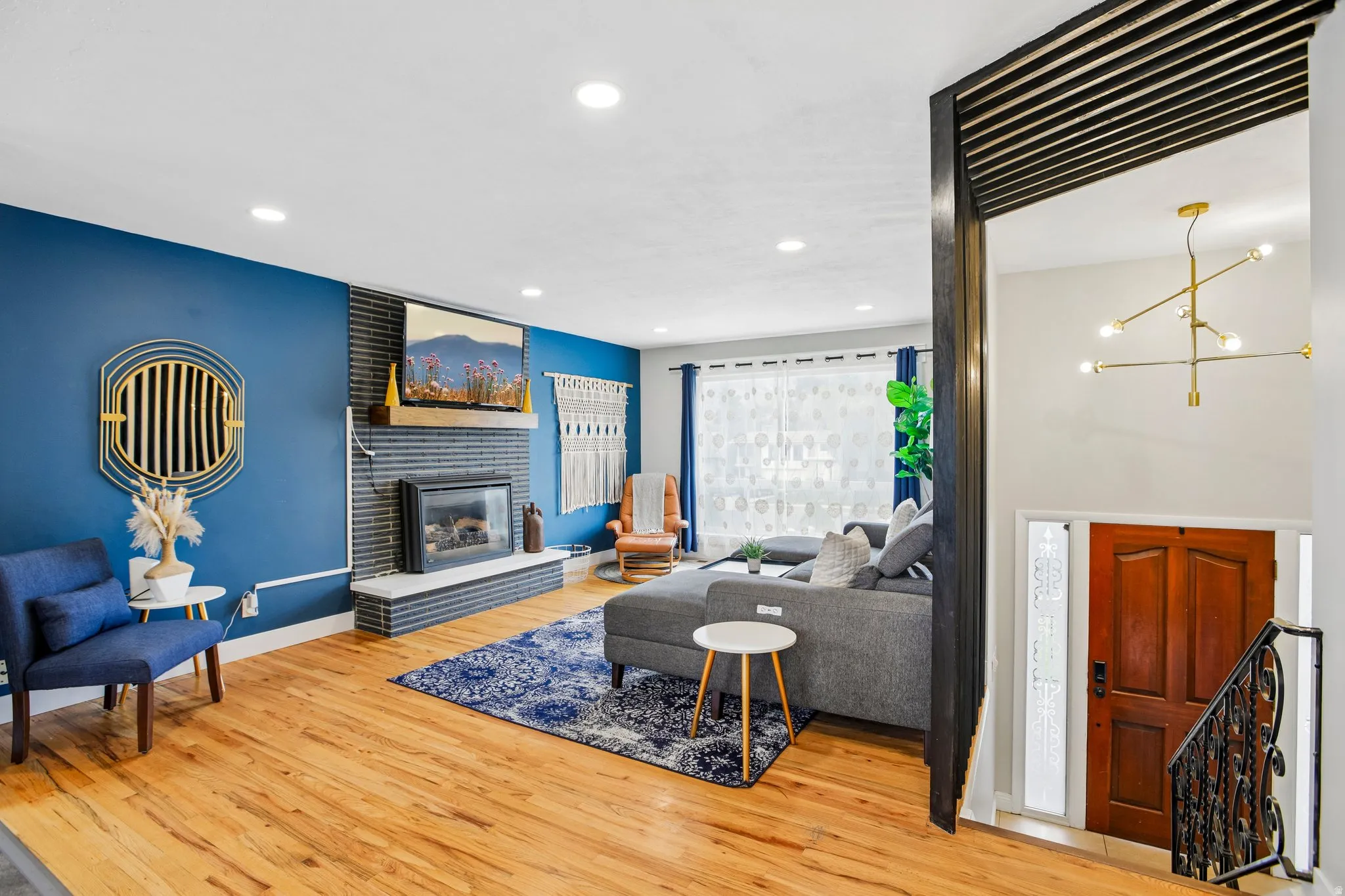 Living area featuring wood-finish flooring, a fireplace with a stone surround and hearth, and recessed lighting