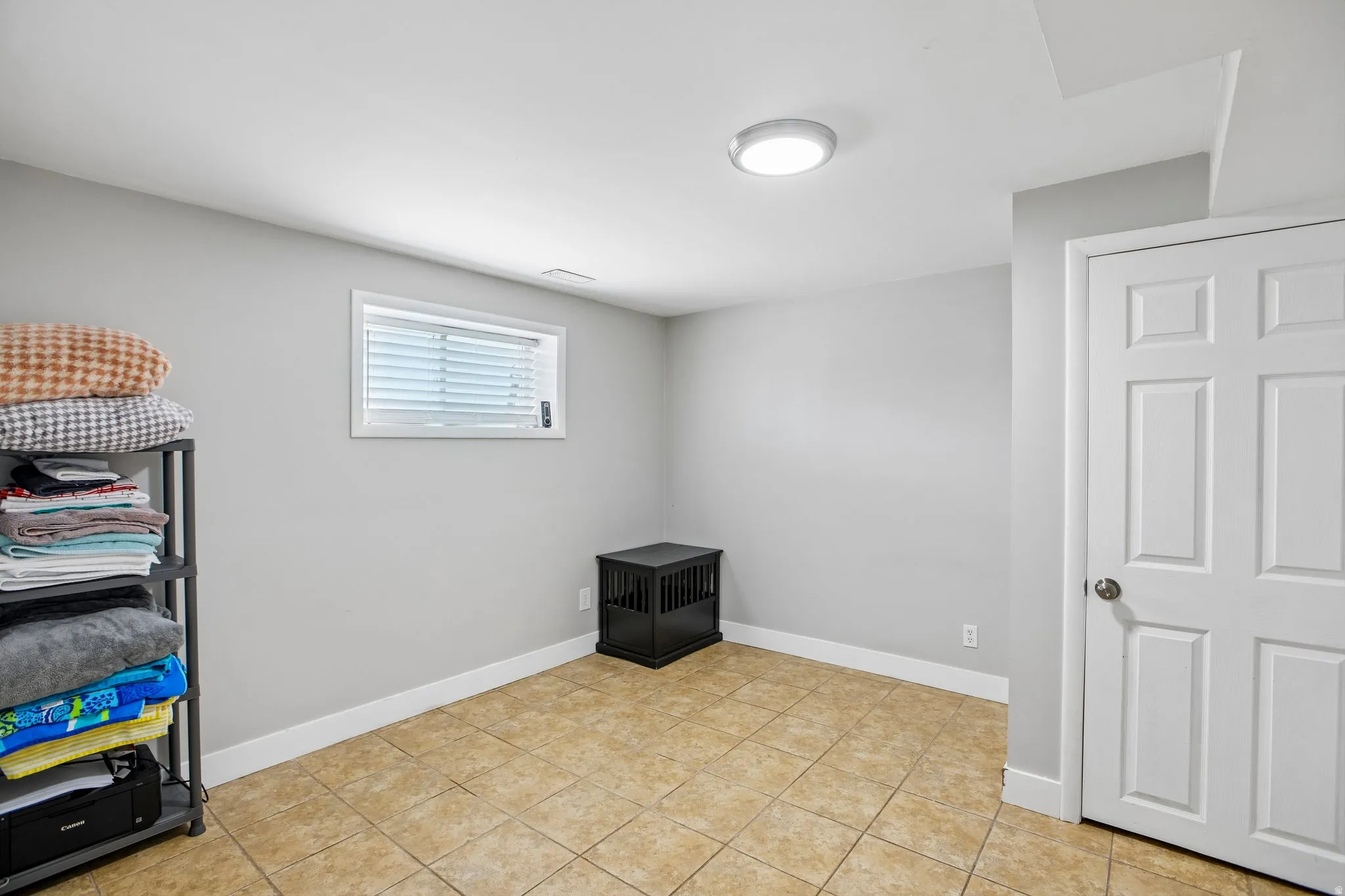 Recessed window with white blinds, neutral wall paint, white trim, and light-toned tile flooring