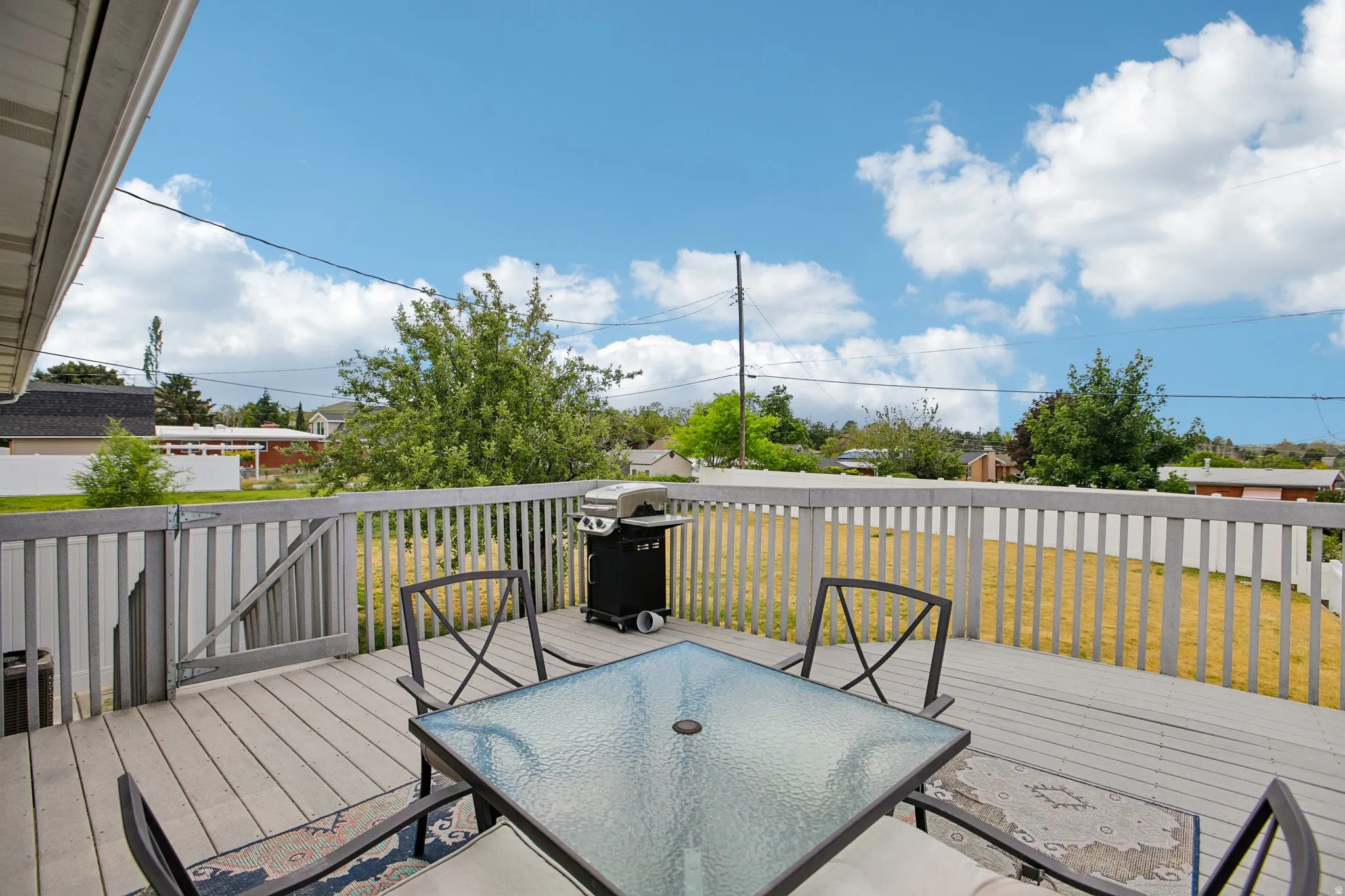 Expansive outdoor wood-finish deck featuring a full railing system and a gate