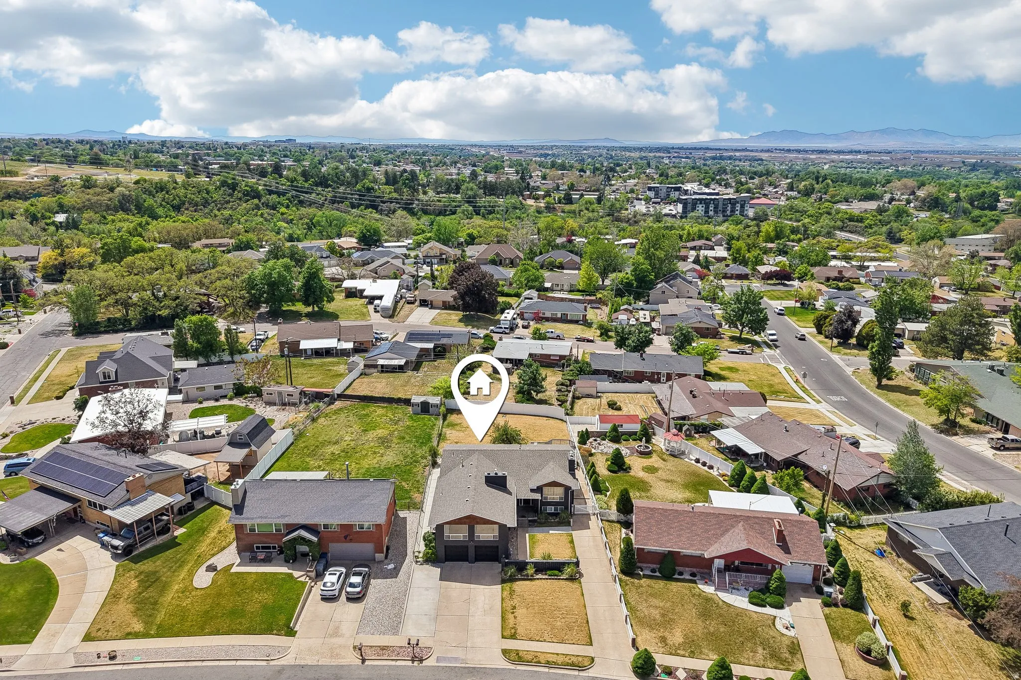 Residential neighborhood with mature trees and mountain backdrop