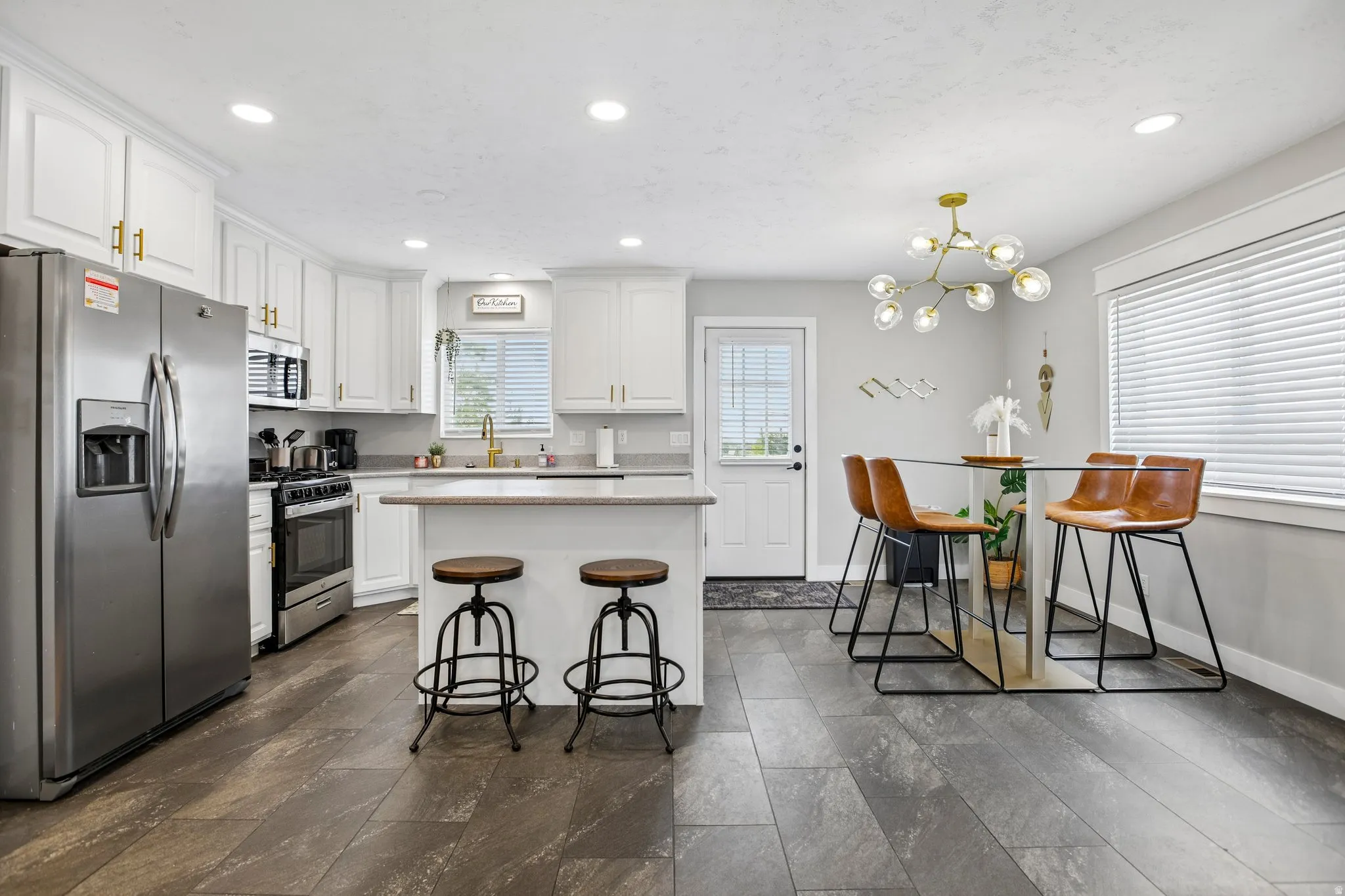 Modern eat-in kitchen with wood-finish flooring, white cabinetry, and stainless steel appliances