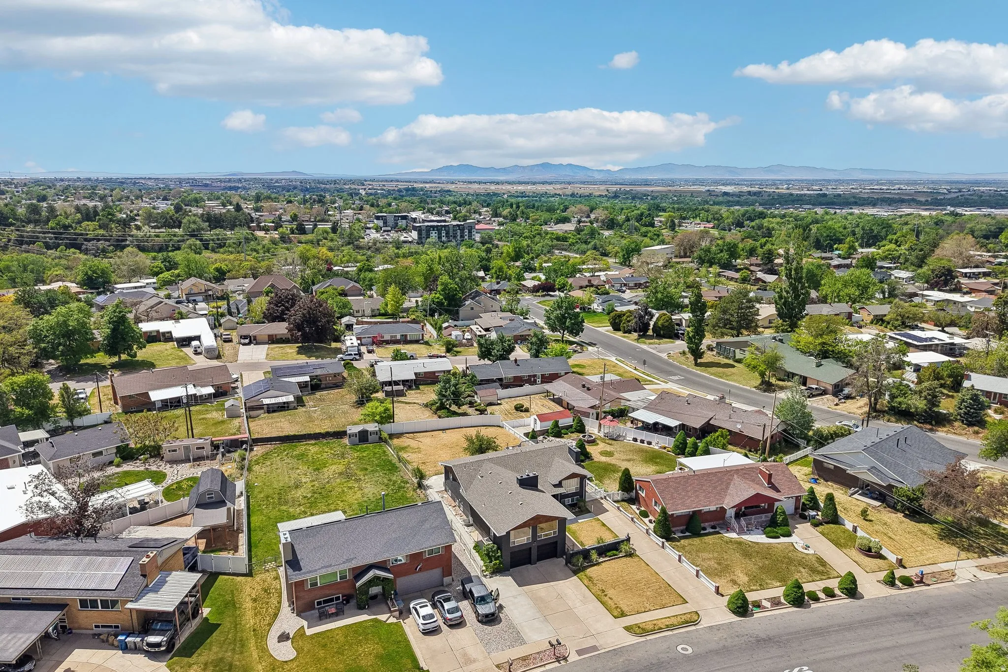 Residential neighborhood with established trees and surrounding mountainous terrain