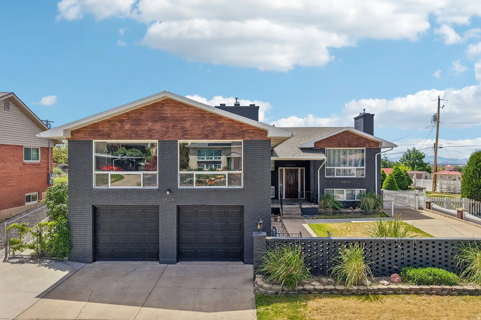 Contemporary facade featuring dark brick, wood-paneled gables, and multiple large windows