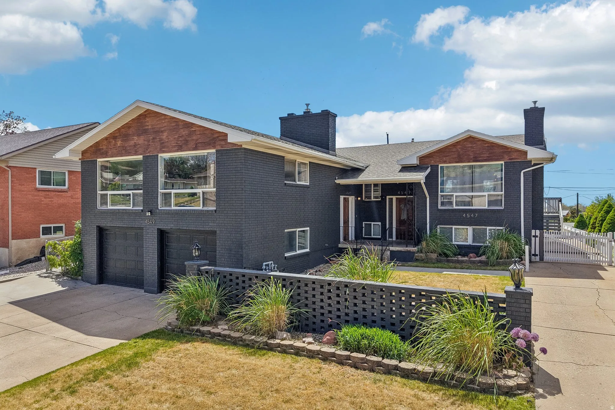 Modern two-story residence featuring a dark brick exterior, prominent front-facing windows, and an integrated two-car garage