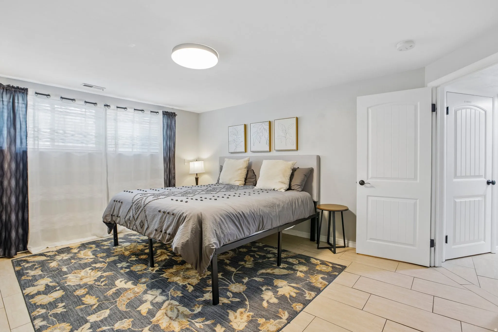 Bedroom featuring light wall color, a flush-mount ceiling light, and two white paneled doors with black hardware
