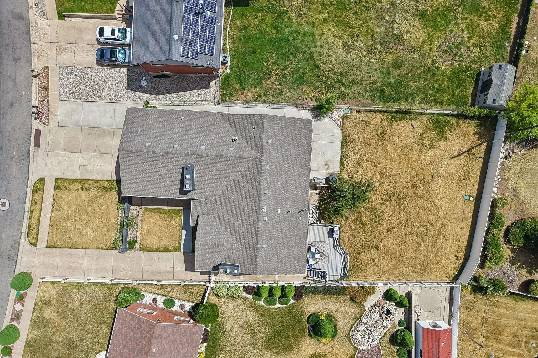 Property featuring a gray shingle roof, a concrete driveway, and an expansive rear yard with a small patio area