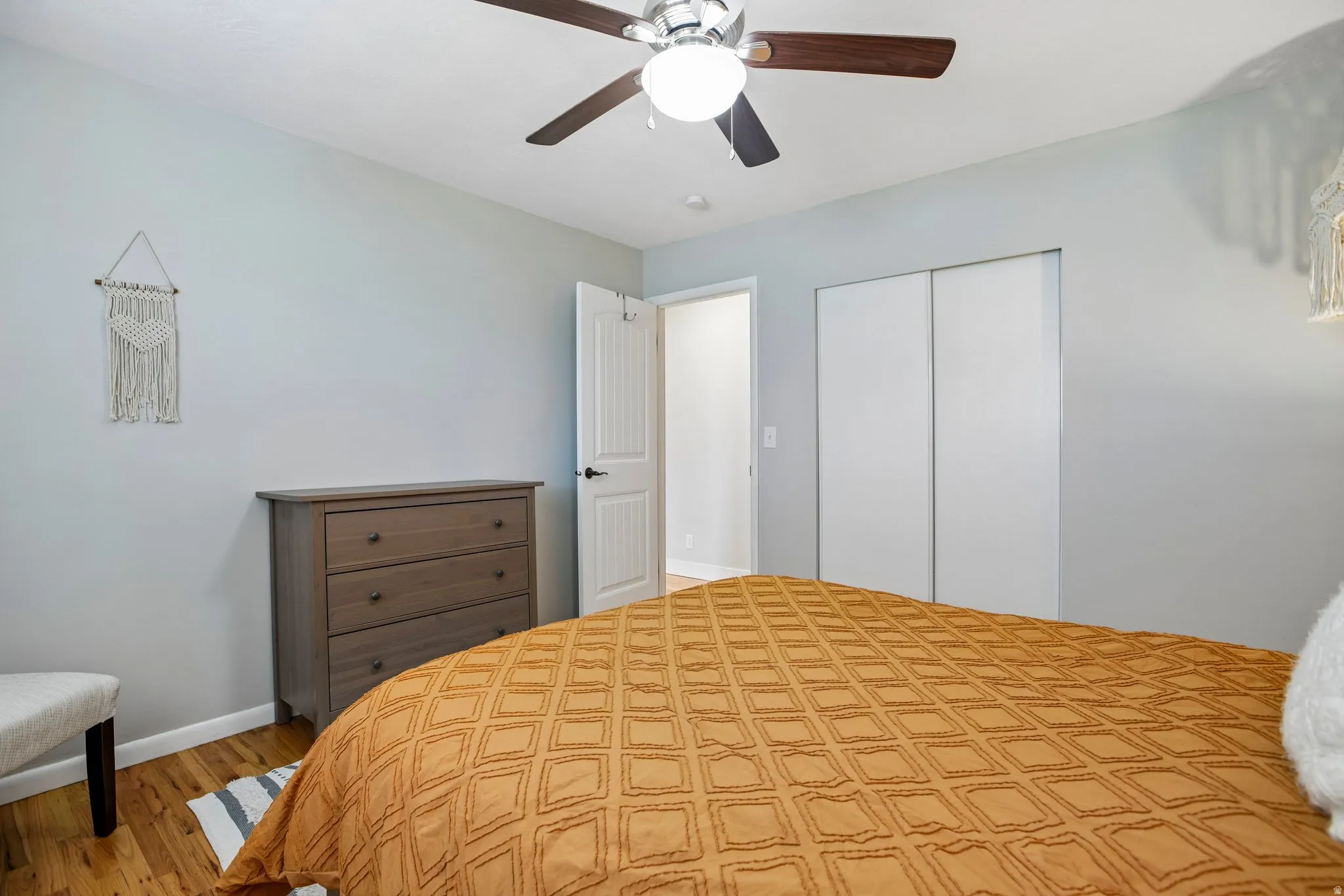 Bedroom featuring wood-finish flooring, a ceiling fan with integrated lighting, and light gray walls