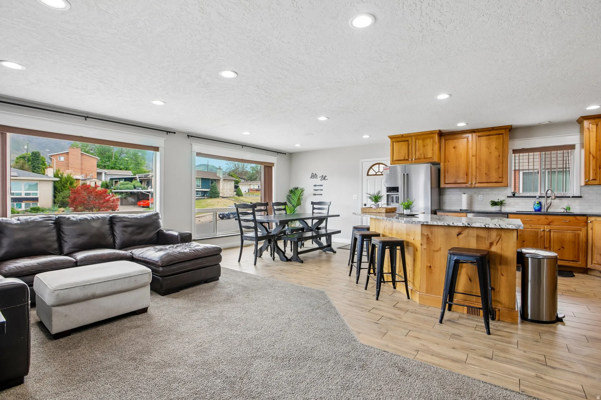 Open-concept living space featuring wood-finish flooring, recessed lighting, and large picture windows