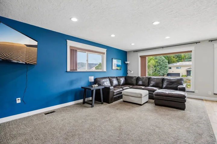 Living area featuring a blue accent wall, recessed lighting, and expansive windows