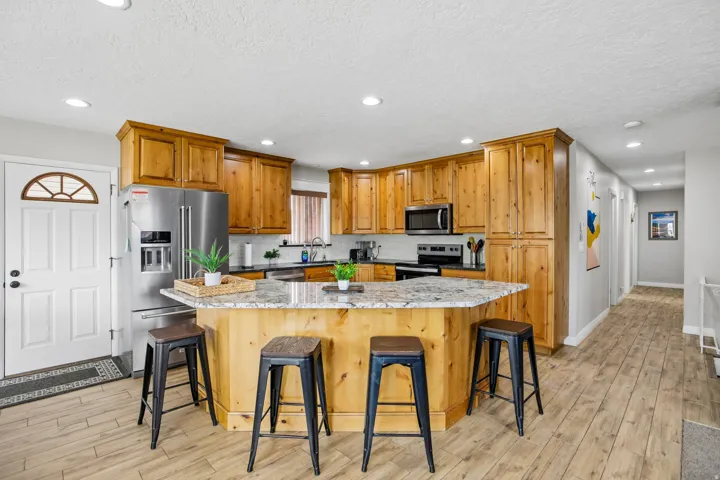 Kitchen featuring wood cabinetry, stainless steel appliances, and a central island with a stone-finish countertop