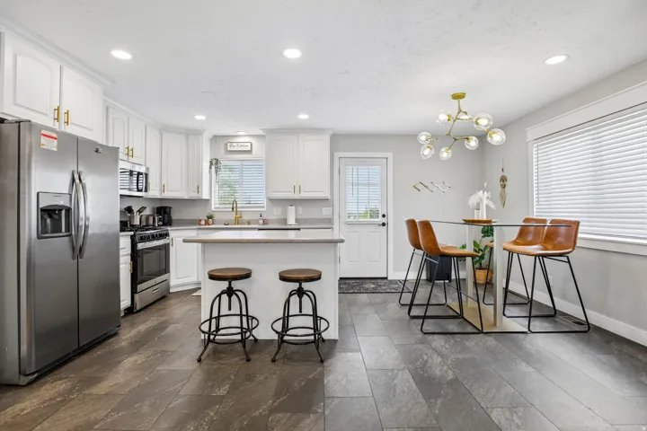Modern eat-in kitchen with wood-finish flooring, white cabinetry, and stainless steel appliances