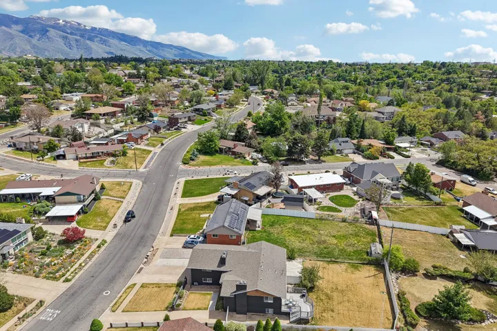 Aerial perspective showcasing a residential area with mature trees and mountain scenery