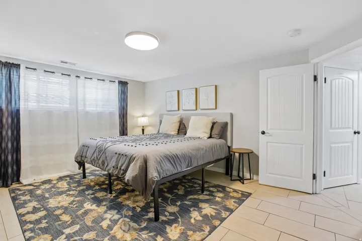 Bedroom featuring light wall color, a flush-mount ceiling light, and two white paneled doors with black hardware
