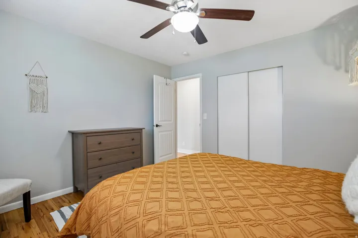 Bedroom featuring wood-finish flooring, a ceiling fan with integrated lighting, and light gray walls