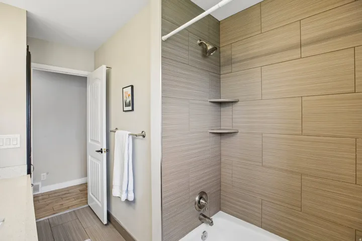 Bathtub and shower combination featuring large format, horizontally laid tile surround in natural tones