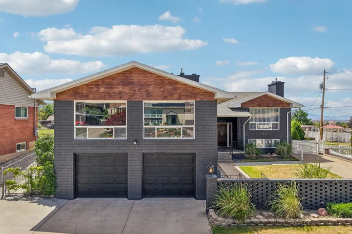 Split-level residence featuring a dark brick exterior with wood-finish gables and a two-car garage