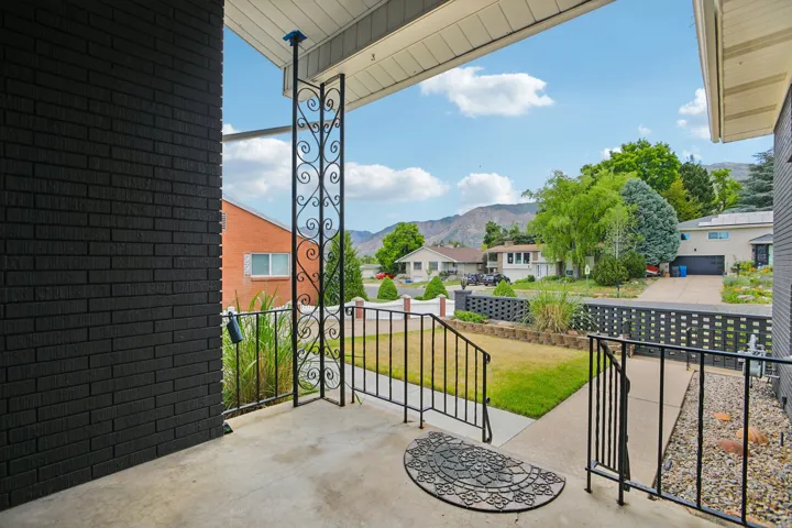 Front porch entry featuring concrete flooring and decorative wrought iron railings