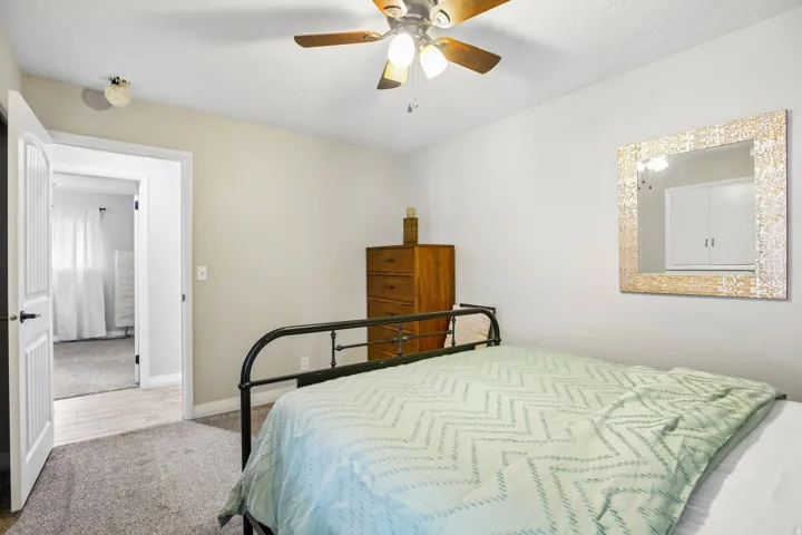 Carpeted room with a ceiling fan, light-colored walls, and a white paneled door