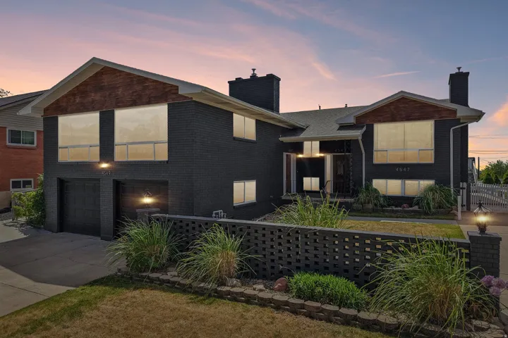 Contemporary split-level exterior featuring dark brick masonry and a contrasting wood-finish gable accent