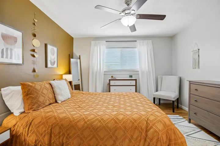 Bedroom featuring a ceiling fan, window with blinds, wood-finish flooring, and a neutral color palette