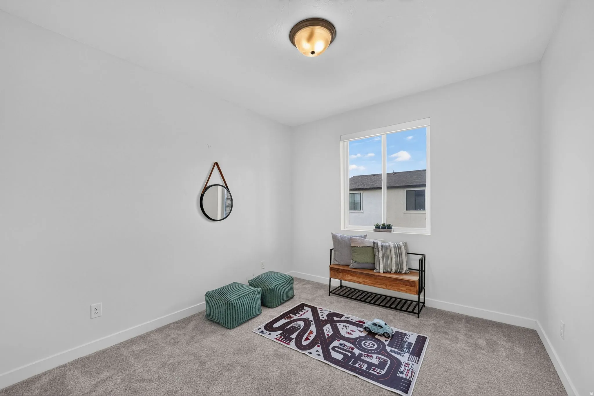 Bright room featuring a large window with white framing, light gray carpeting, and white baseboards