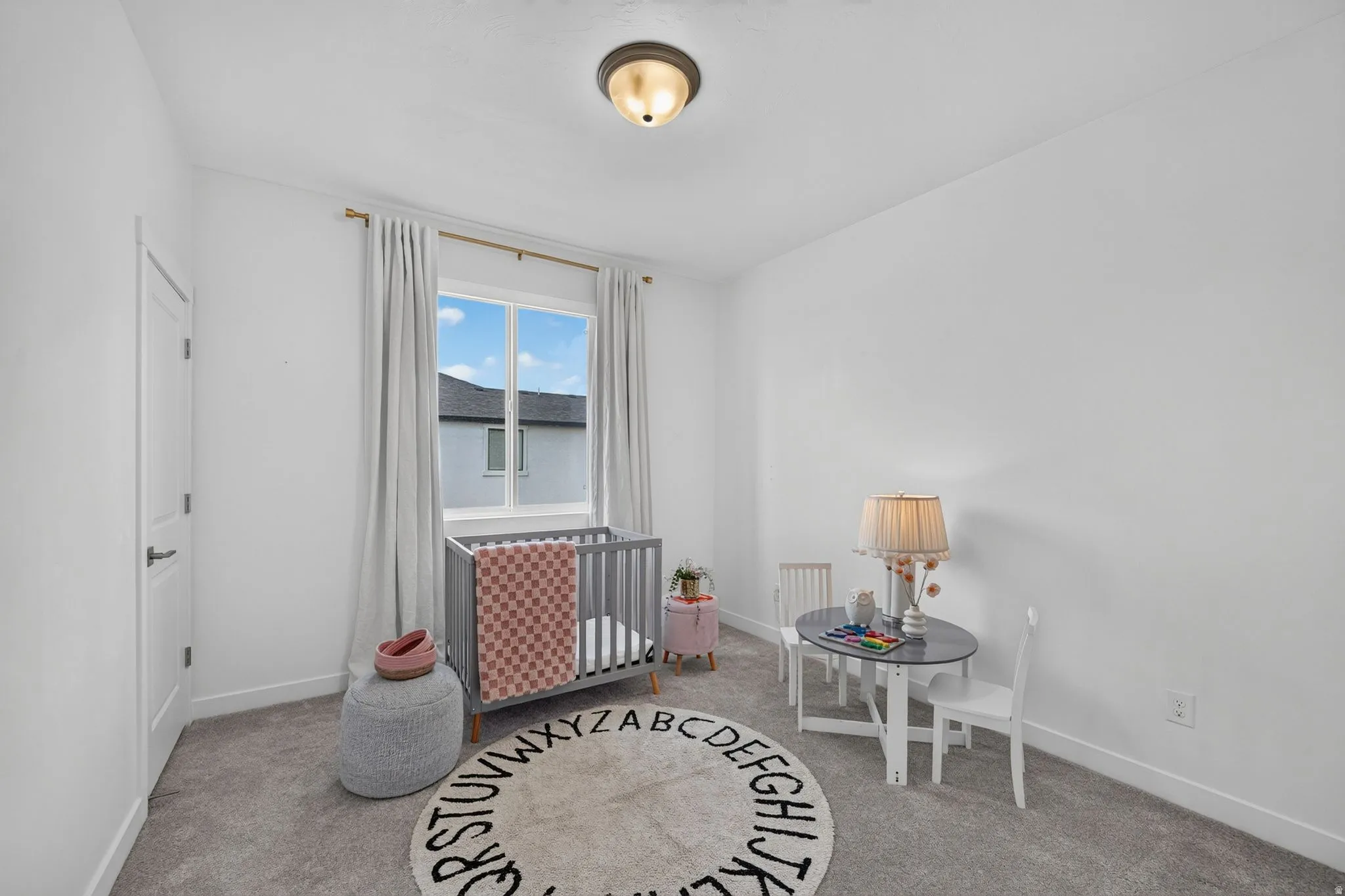Bright room featuring a prominent window with drapes, neutral wall finishes, and ceiling-mounted lighting