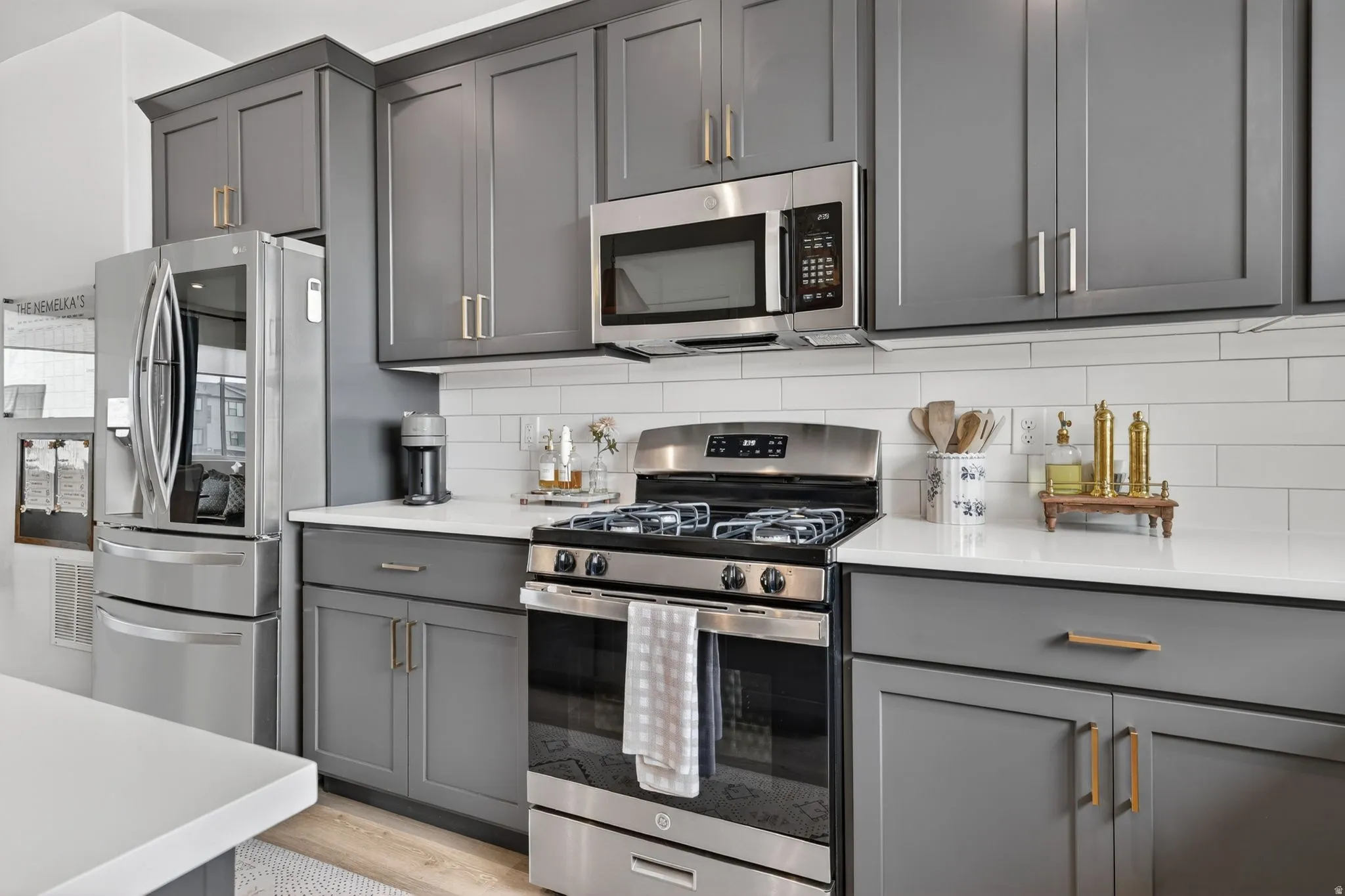 Kitchen featuring stainless steel appliances, grey shaker-style cabinetry, white countertops, and a white subway tile backsplash