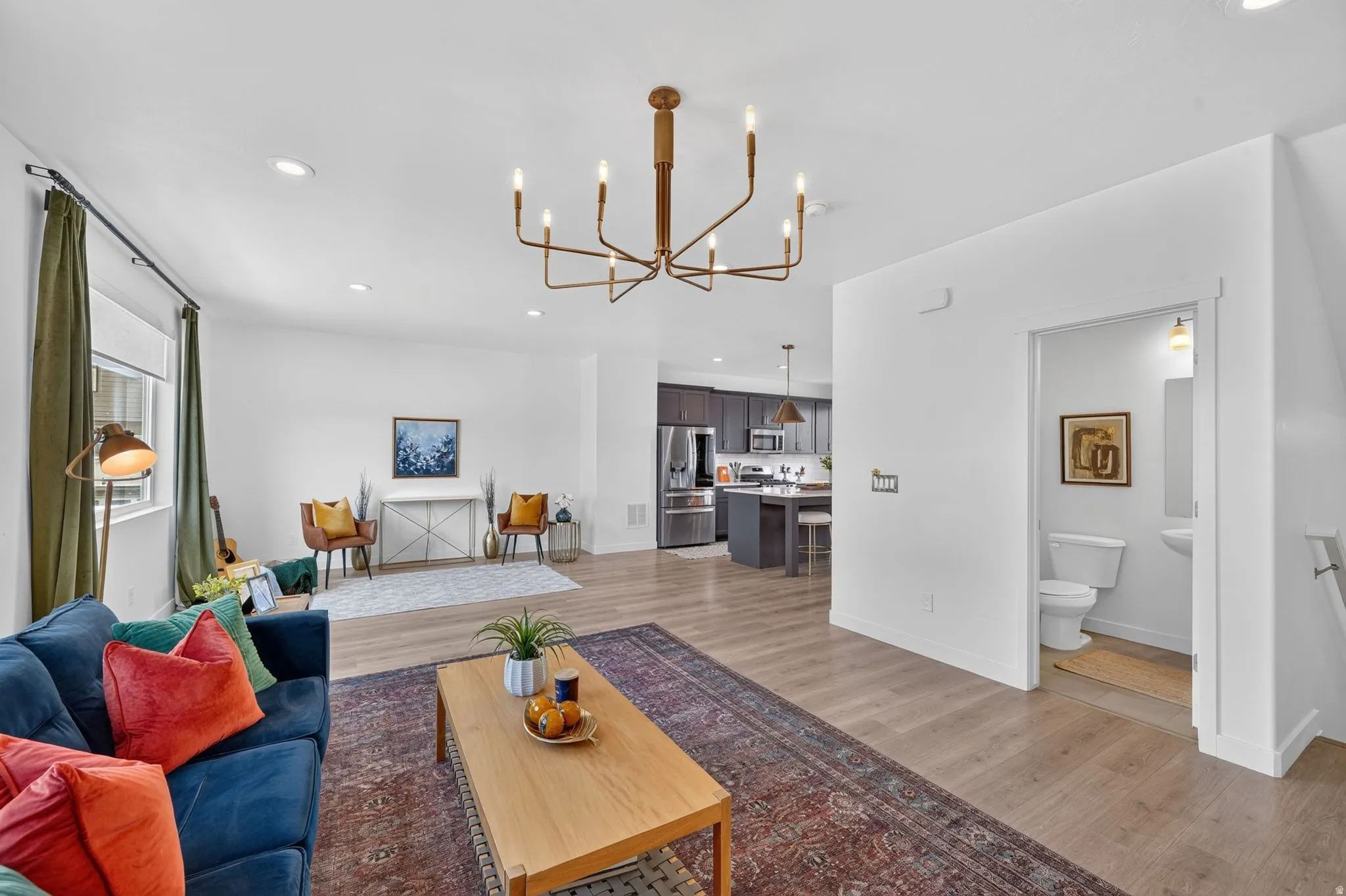 Open-concept living area featuring wood-finish flooring, recessed lighting, and a modern chandelier