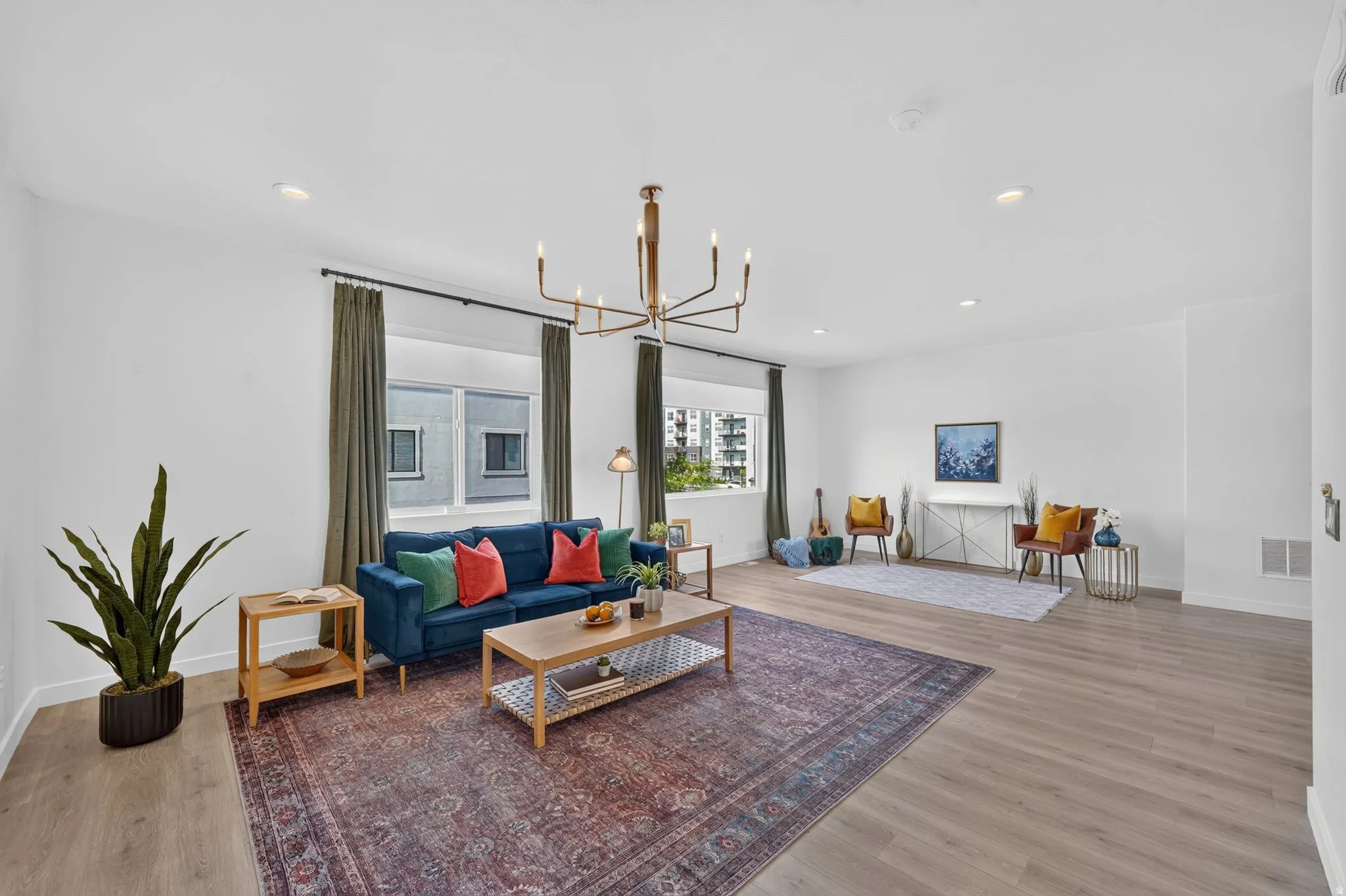 Spacious living area featuring light wood-finish flooring, recessed lighting, and a modern chandelier
