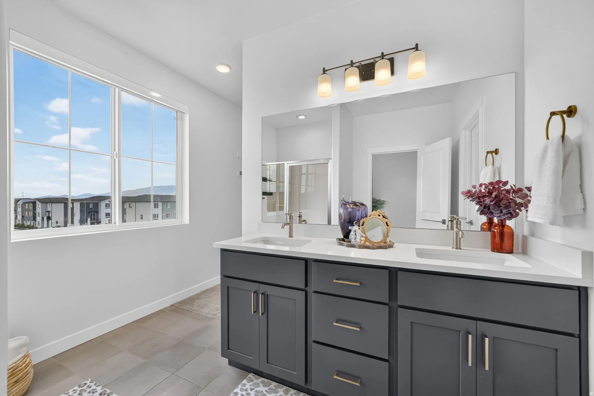 Double vanity with dark cabinetry, integrated sinks, and quartz countertops