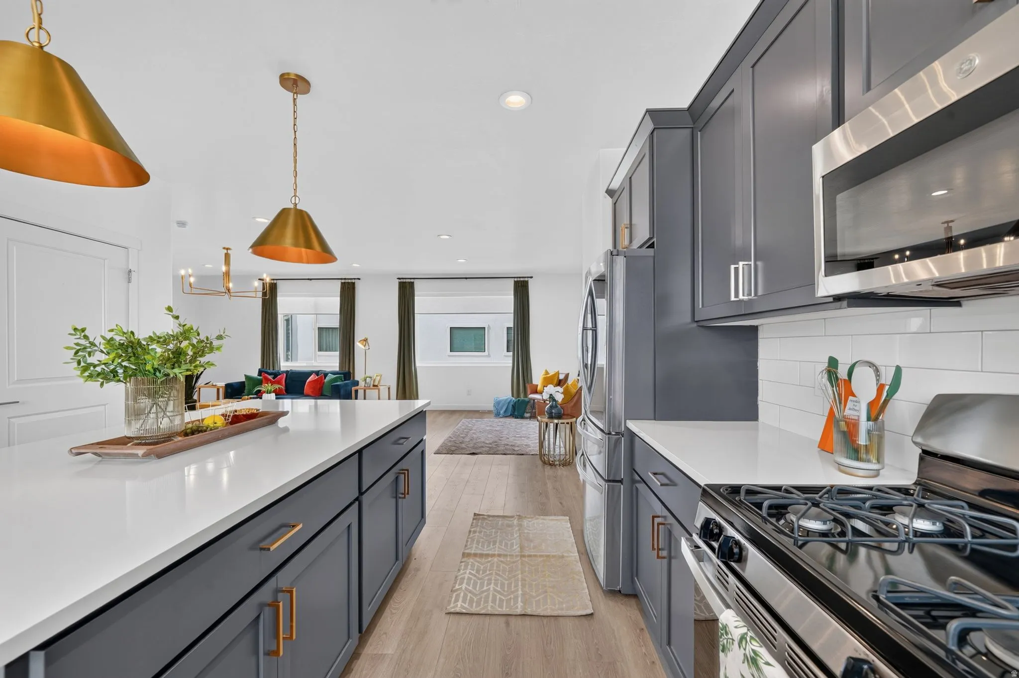 Spacious kitchen featuring an expansive island with white countertop, dark gray cabinetry, and gold hardware