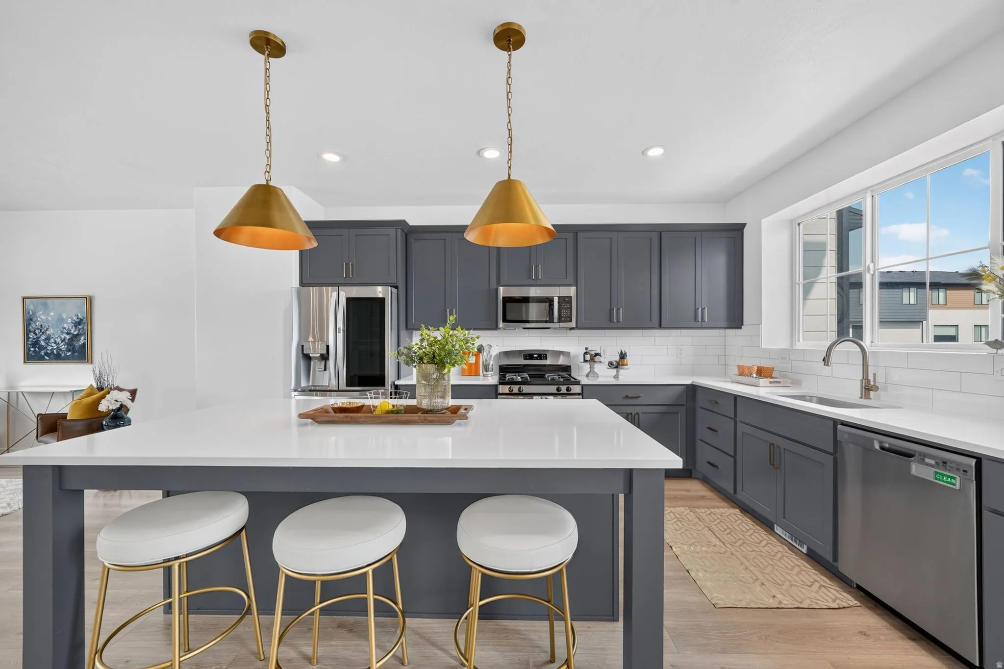 Kitchen featuring an expansive center island with seating, white countertops, dark gray cabinetry, and stainless steel appliances