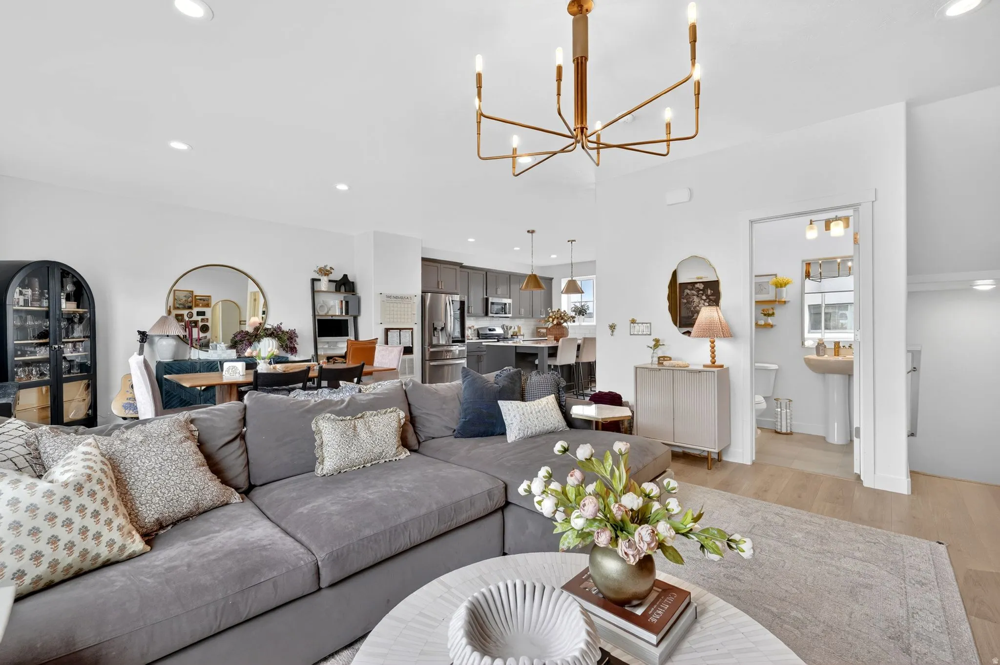 Open-concept living space featuring light wood-finish flooring and a contemporary linear chandelier