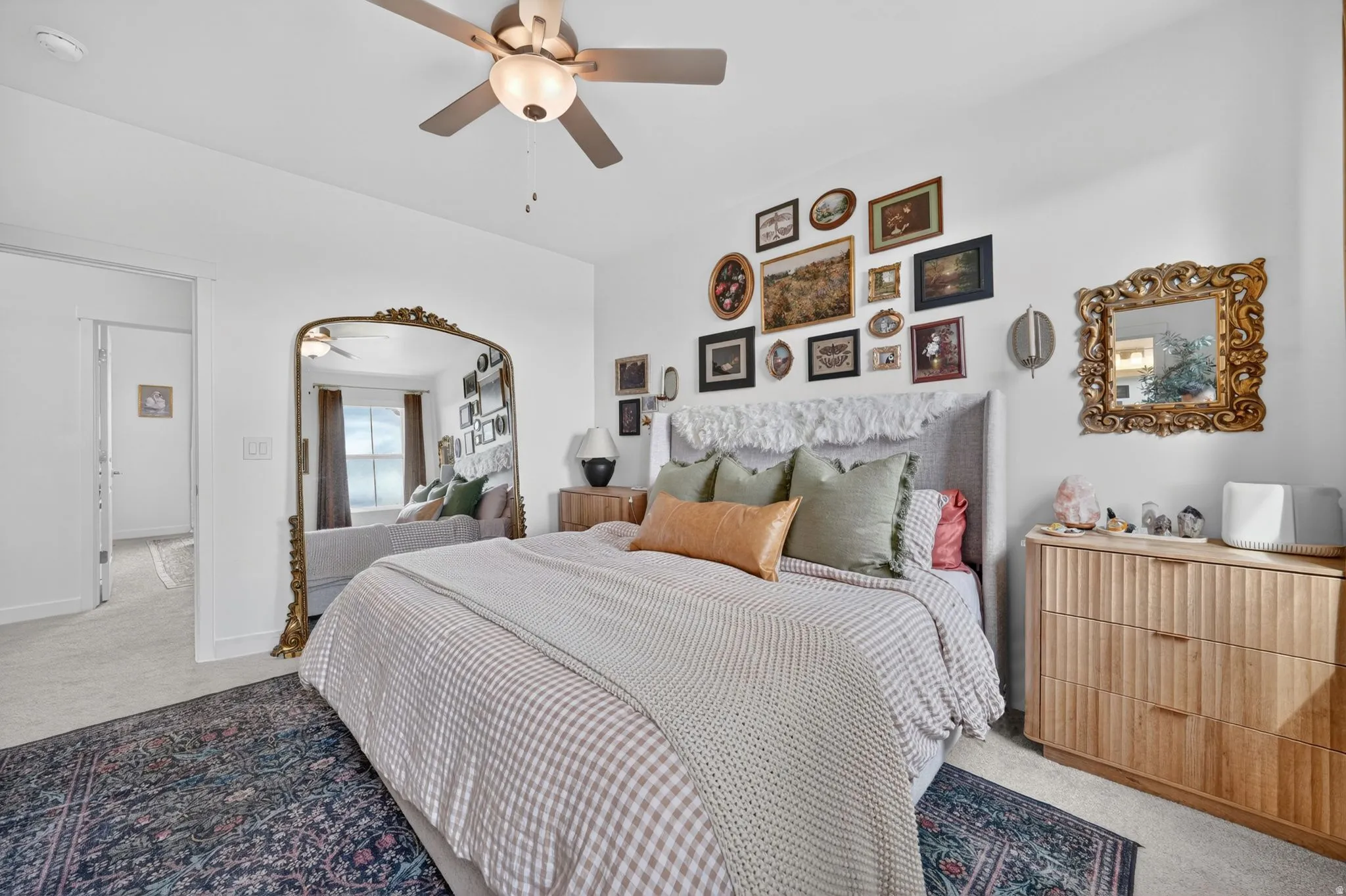Bedroom featuring a ceiling fan, light gray carpet, and a framed mirror