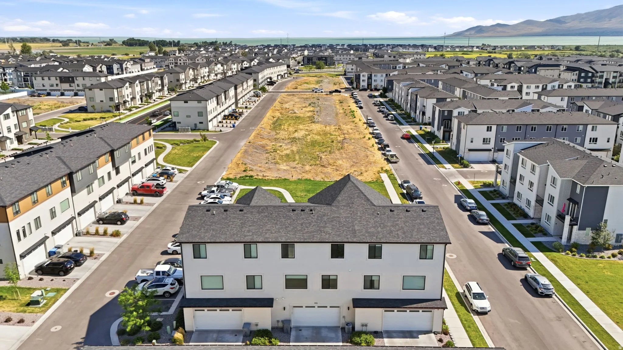Contemporary townhome community featuring multi-story units with attached garages, manicured green spaces, and paved street access