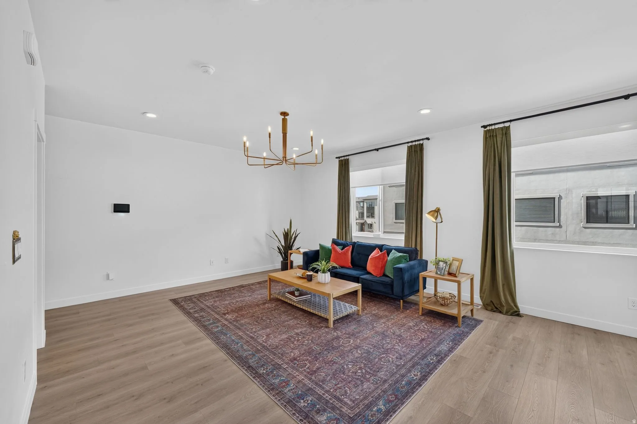 Spacious living area featuring light wood-finish flooring, recessed lighting, and a modern chandelier