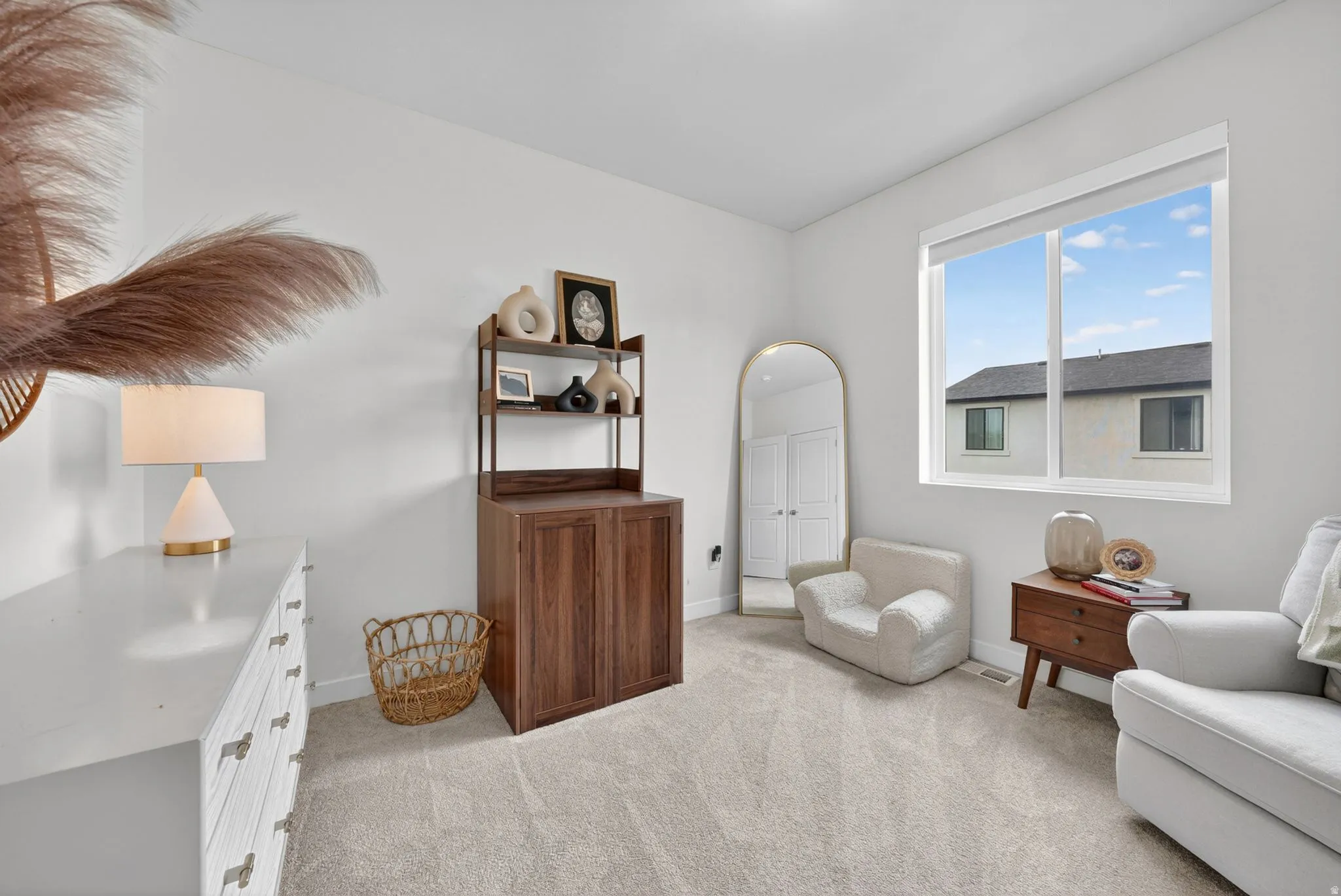 Bright interior space featuring a large window, light-toned walls, and neutral carpeting
