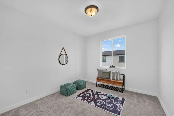 Bright room featuring a large window with white framing, light gray carpeting, and white baseboards