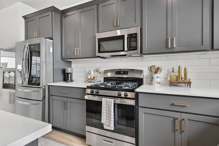 Kitchen featuring stainless steel appliances, grey shaker-style cabinetry, white countertops, and a white subway tile backsplash