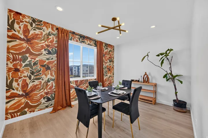 Dining area featuring a prominent accent wall with a floral pattern, wood-finish flooring, and a modern linear chandelier