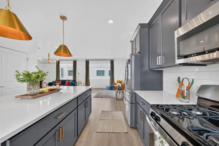 Spacious kitchen featuring an expansive island with white countertop, dark gray cabinetry, and gold hardware
