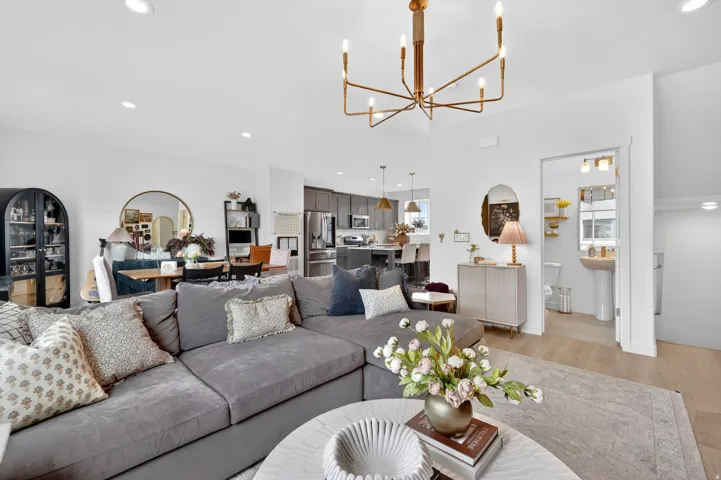 Open-concept living space featuring light wood-finish flooring and a contemporary linear chandelier
