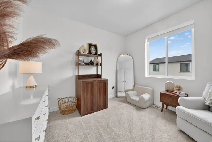 Bright interior space featuring a large window, light-toned walls, and neutral carpeting