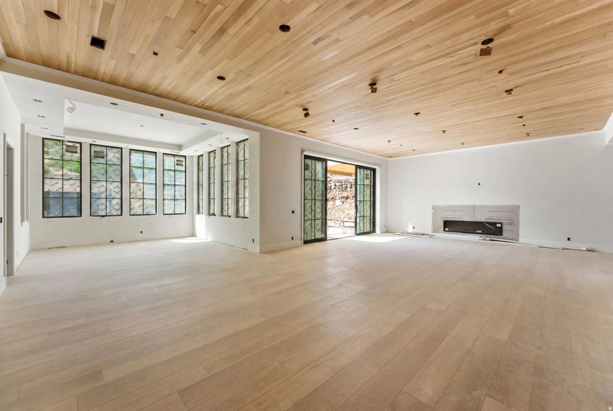 Expansive room featuring wood-finish flooring and a wood plank ceiling with recessed lighting
