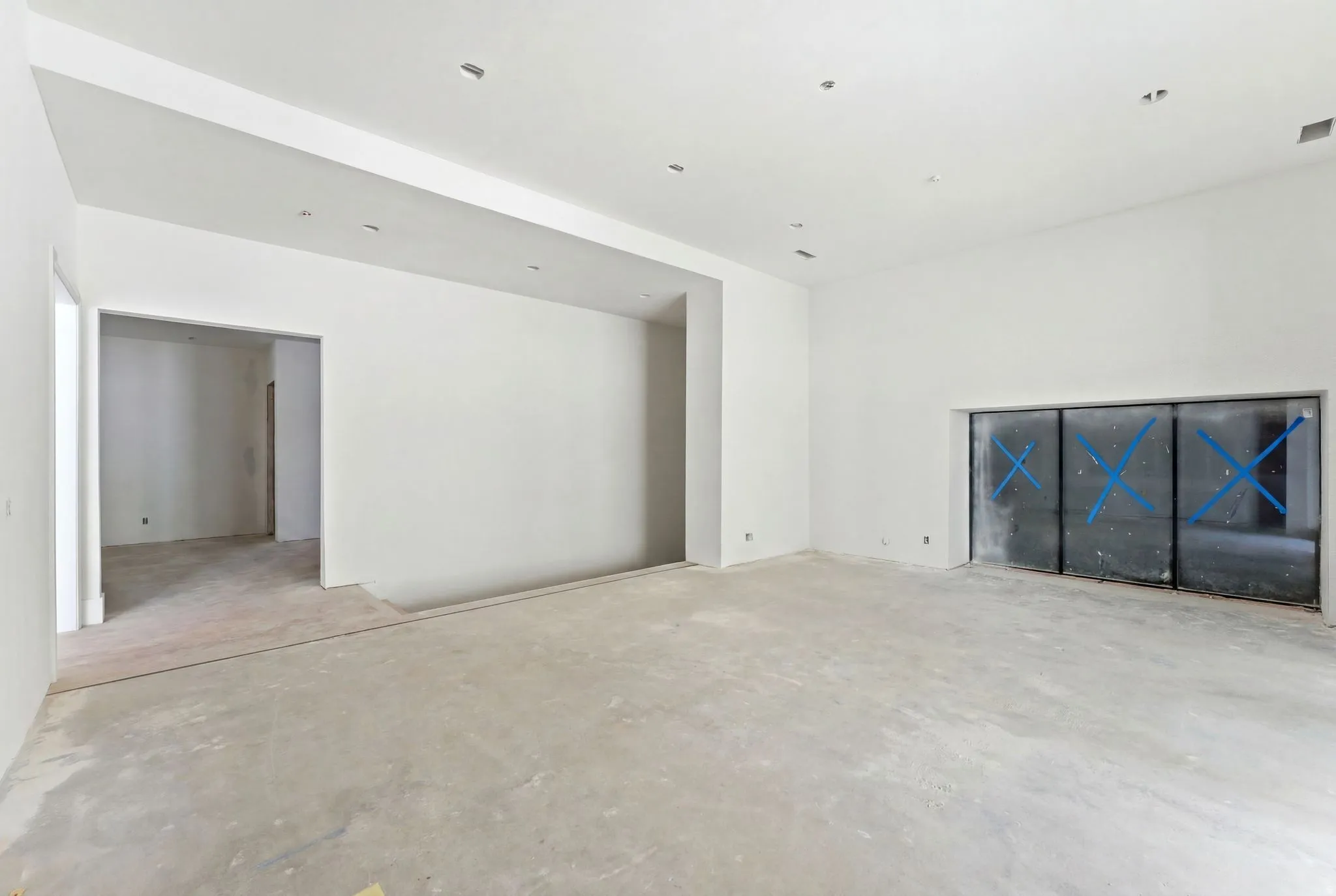 Spacious room with high ceilings, recessed lighting, and a large built-in niche featuring three panels