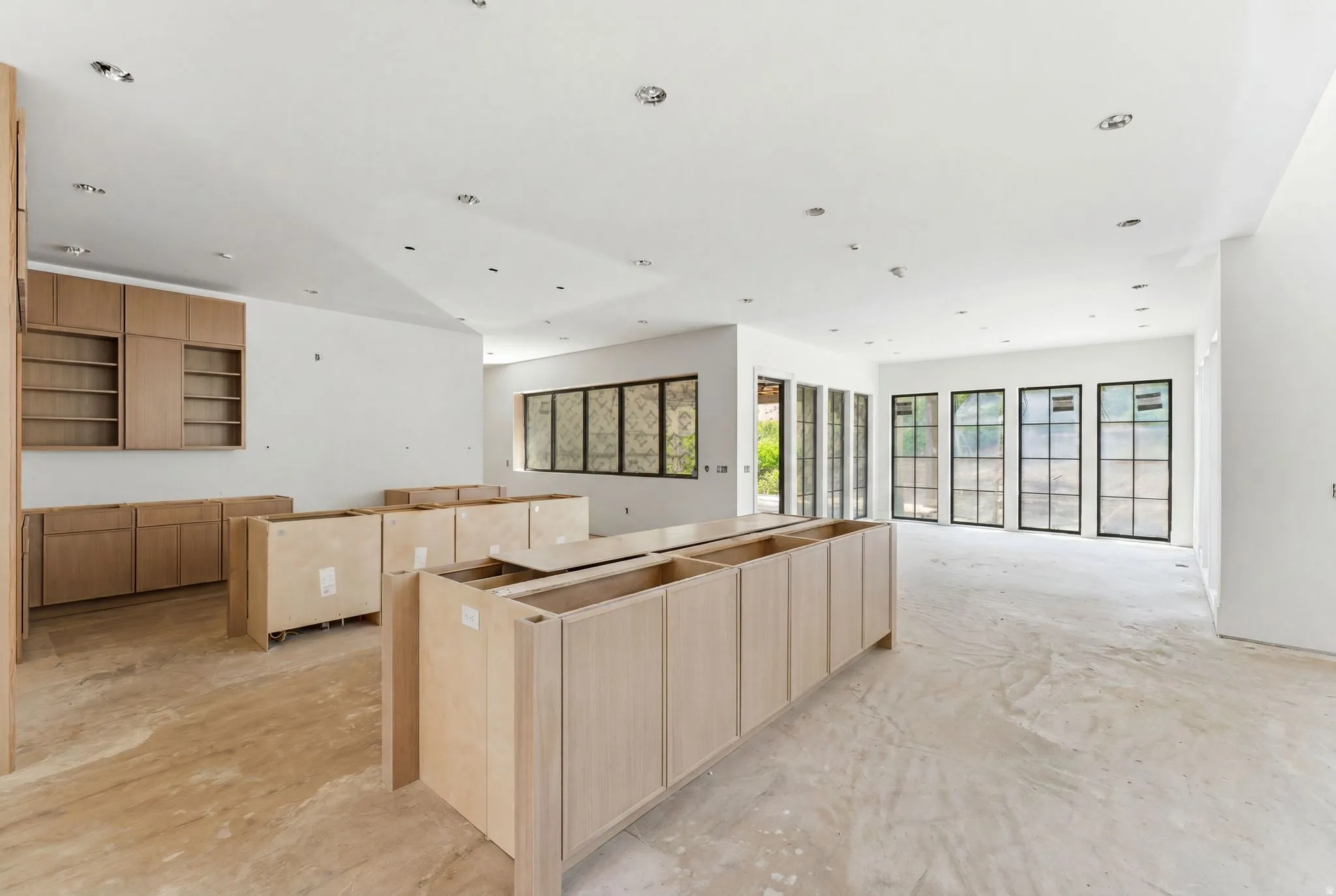 Spacious open-concept interior featuring light-toned cabinetry, recessed lighting, and expansive multi-pane windows