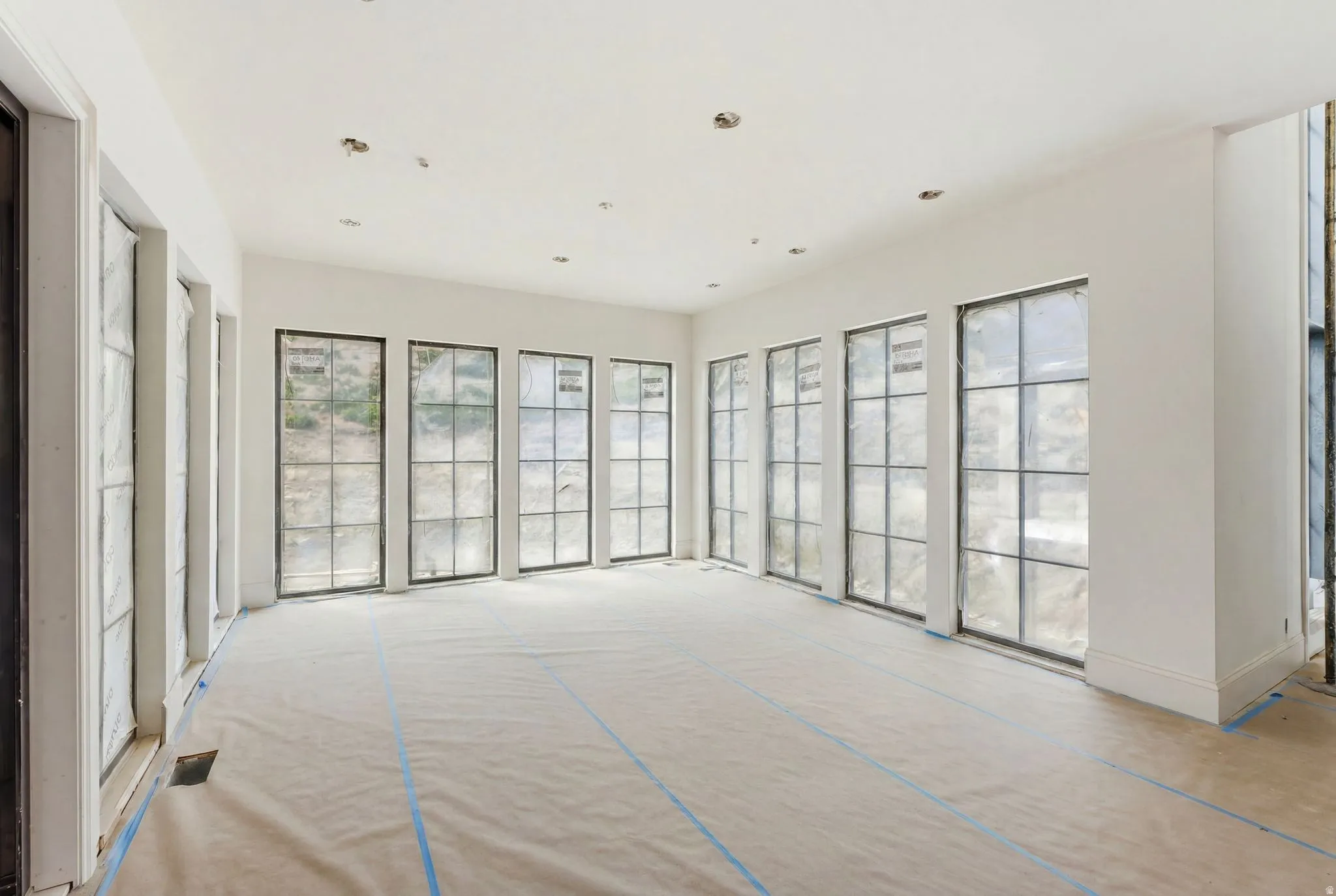 Spacious room featuring multiple large grid-pattern windows, recessed lighting, and crisp white walls