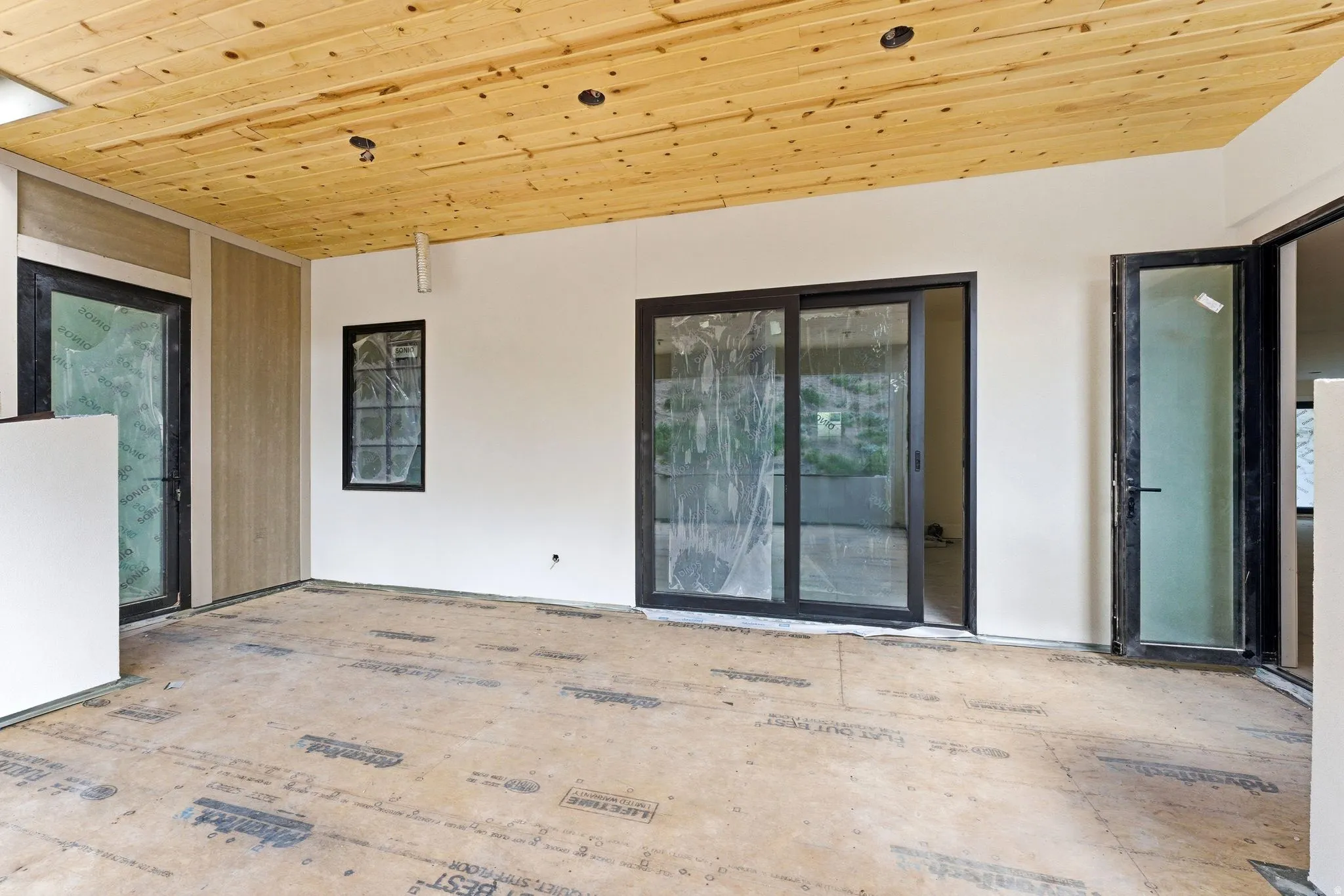 Spacious indoor-outdoor area with a natural wood ceiling, multiple door openings, and a large sliding glass door