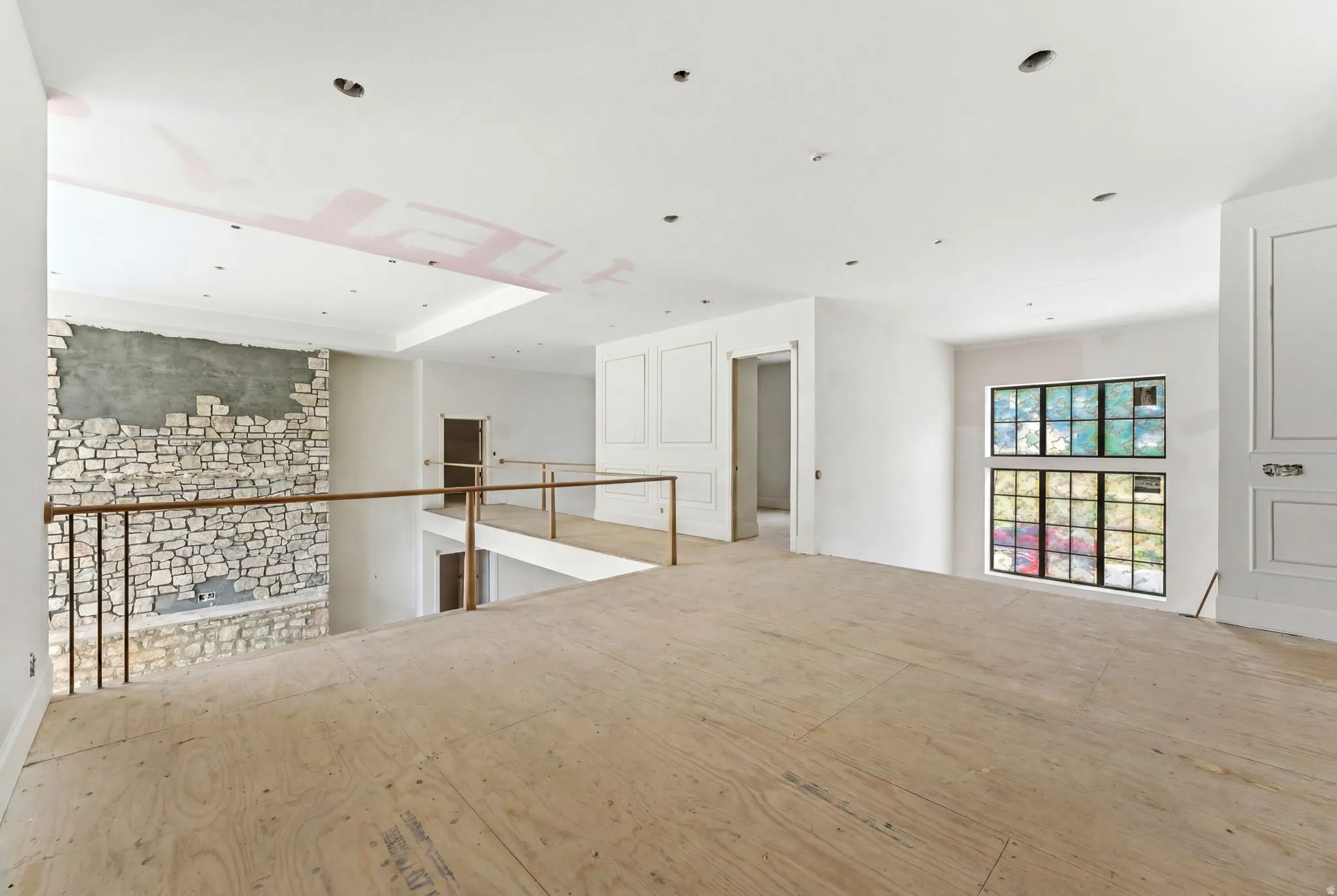 Spacious upper-level area featuring a stone accent wall, recessed lighting, and a prominent window array with black framing